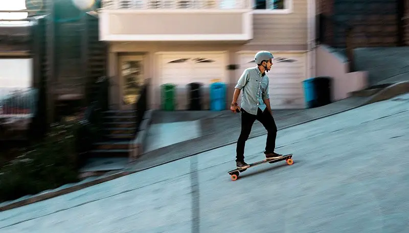 young man riding on an electric skateboard uphill