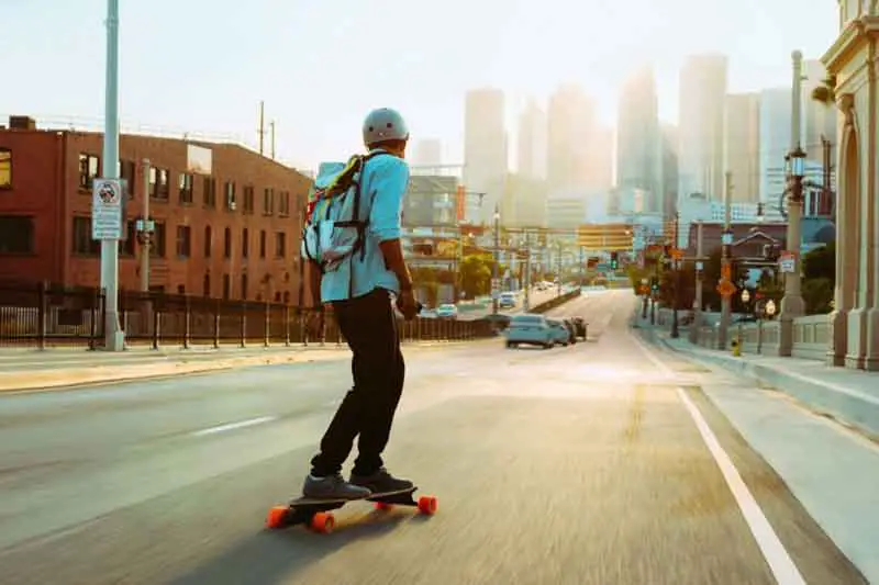 man commuting on electric skateboard through the city